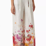 Woman wearing floral print blouse and wide-leg pants with brown handbag — Leo Lin | Endless UAE