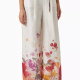 Woman wearing floral print blouse and wide-leg pants with brown handbag — Leo Lin | Endless UAE