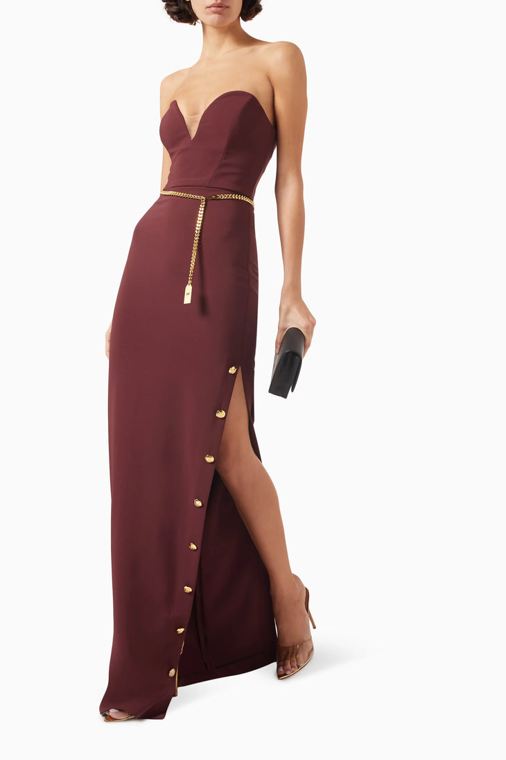 Elegant burgundy strapless maxi dress with plunging neckline, gold chain belt, and thigh-high slit with button details — Elisabetta Franchi | Endless UAE