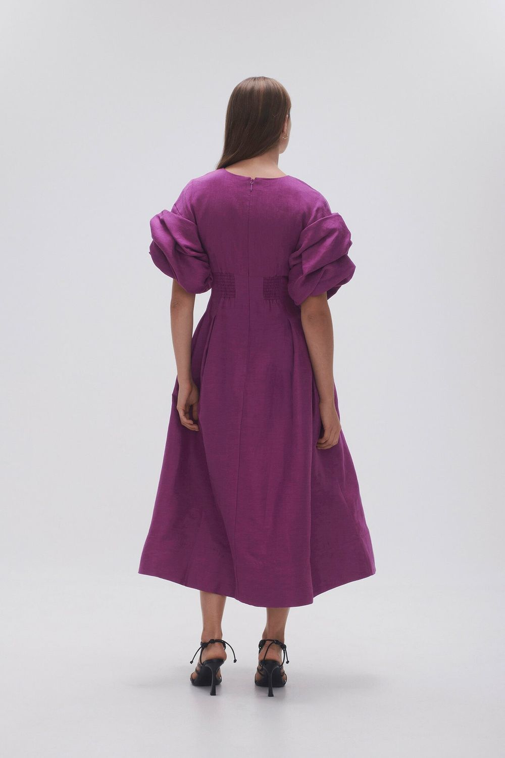 Woman wearing Adelie Puff Sleeve Midi Dress in plum with black strappy sandals — Aje | Endless UAE