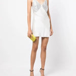 White slip dress with studded chest panel worn with yellow clutch and black sandals — De La Vali | Endless UAE
