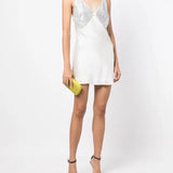 White slip dress with studded chest panel worn with yellow clutch and black sandals — De La Vali | Endless UAE