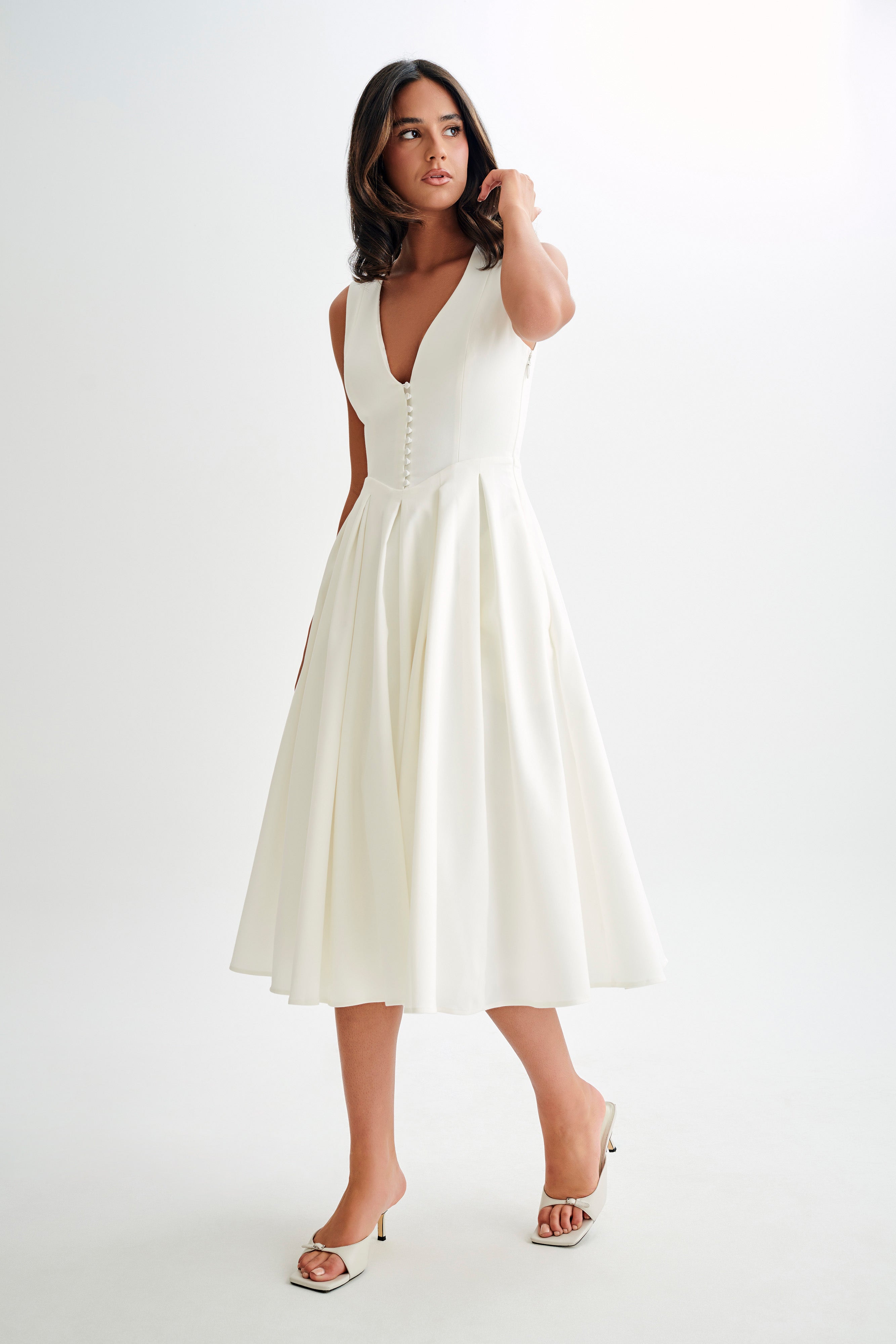 Woman wearing cream sleeveless midi dress with button front — Meshki | Endless UAE