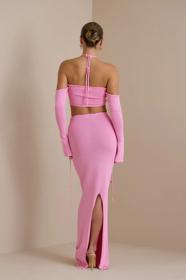 Rear view of woman wearing pink halter crop top and maxi skirt two-piece set with off-shoulder sleeves and back slit — Endless | Endless UAE