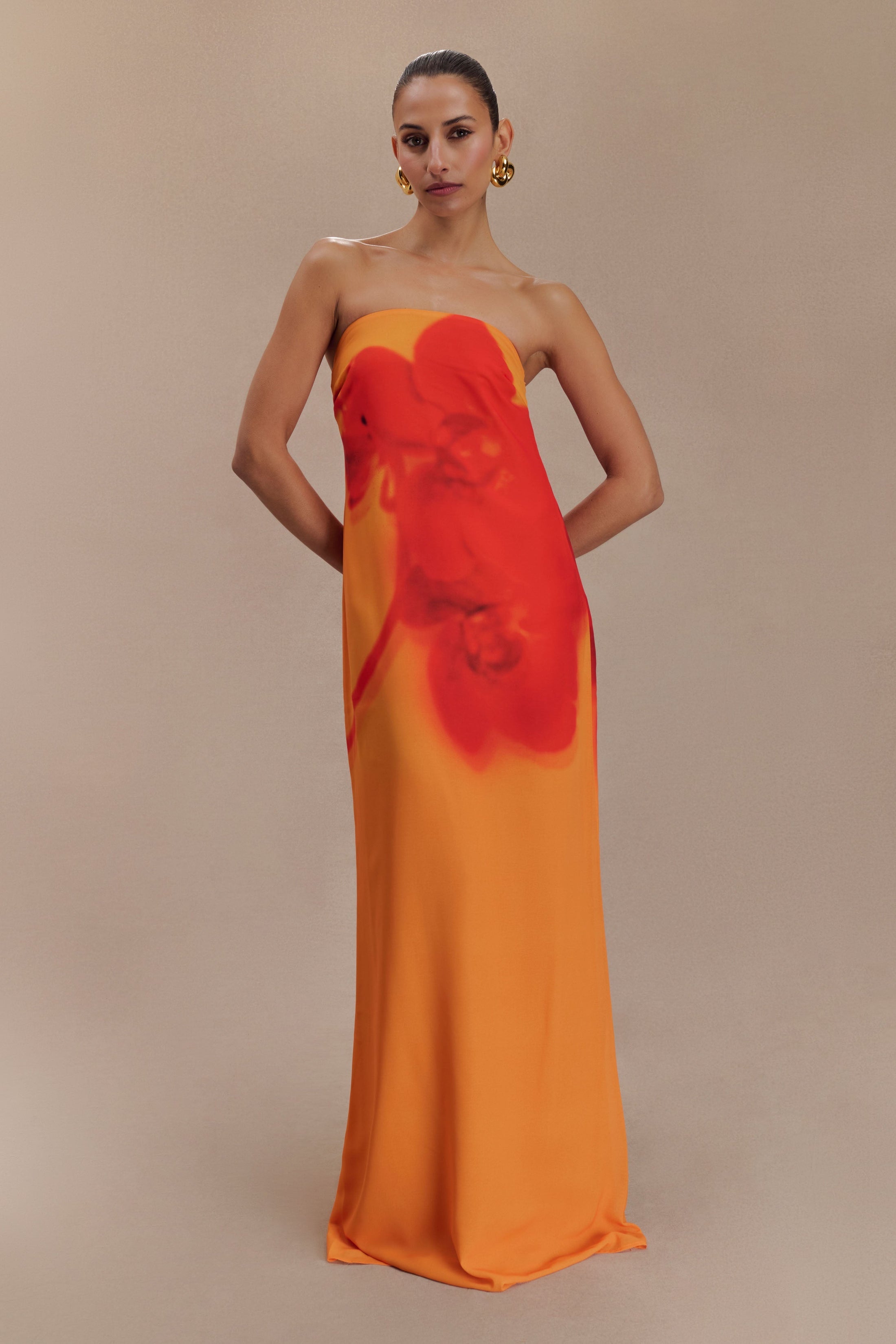 Woman wearing a strapless orange and red ombre chiffon maxi dress with gold hoop earrings — Meshki | Endless UAE