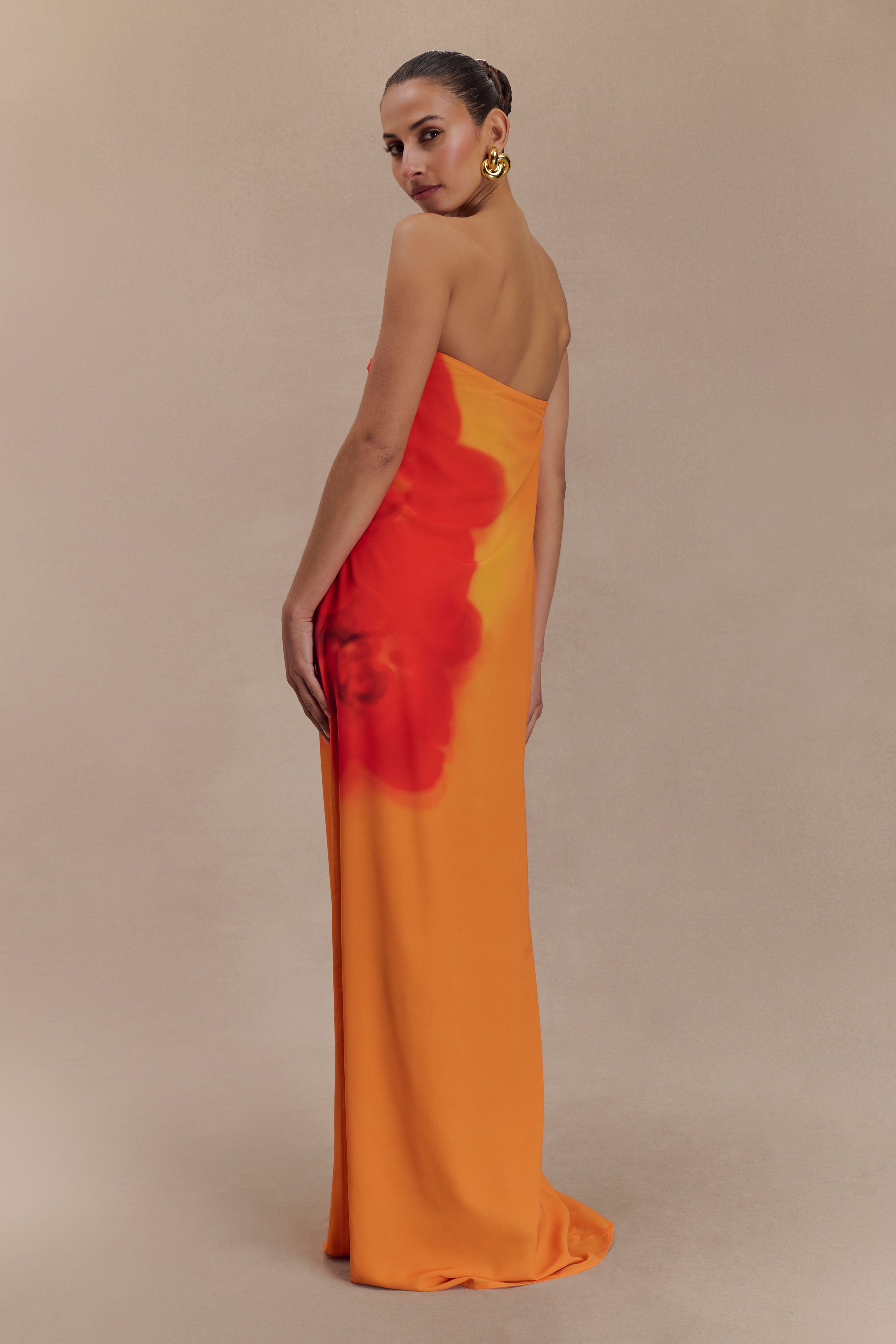Woman wearing a strapless orange and red ombre chiffon maxi dress with gold hoop earrings — Meshki | Endless UAE