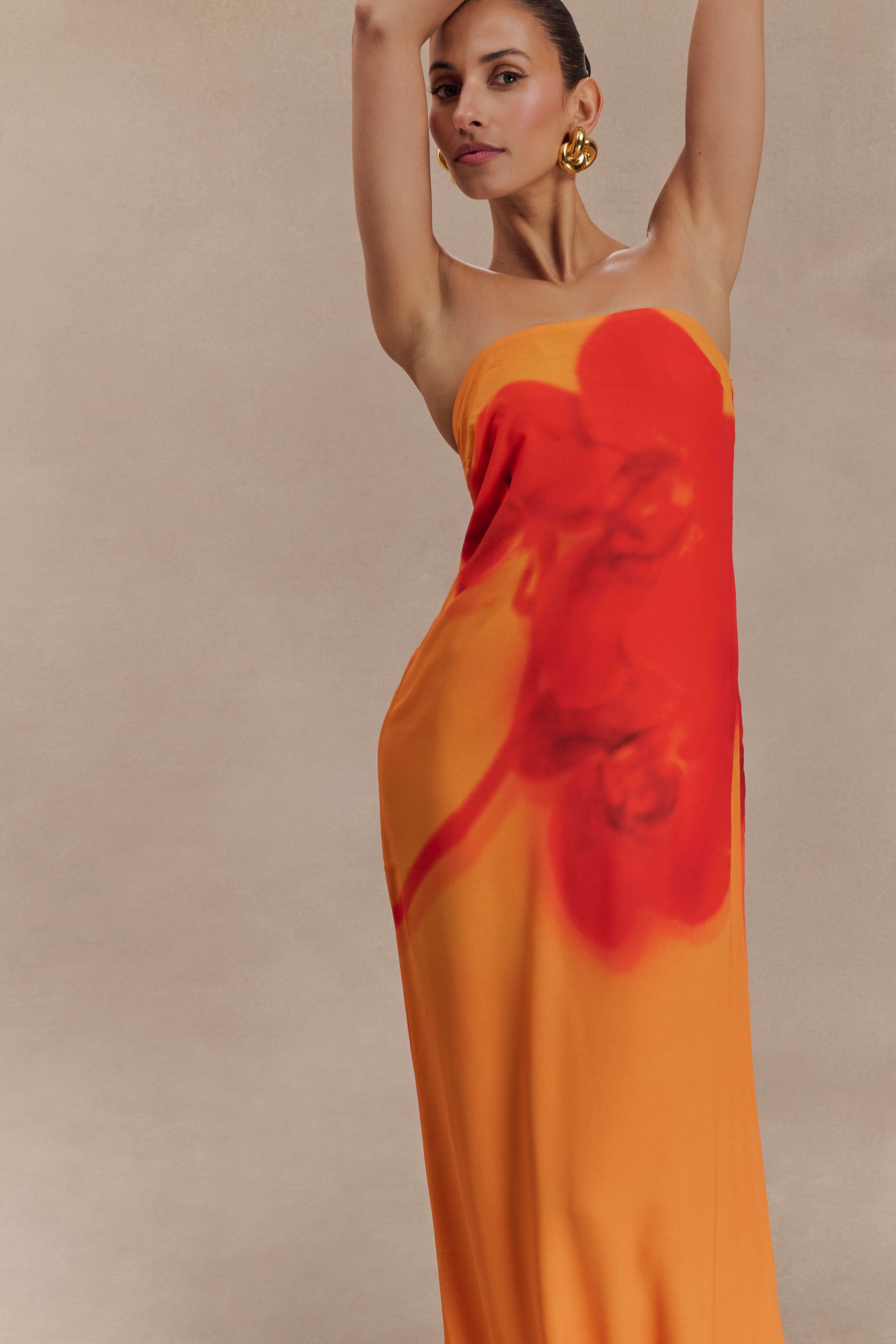 Woman wearing a strapless orange and red ombre chiffon maxi dress with gold hoop earrings — Meshki | Endless UAE
