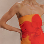 Woman wearing a strapless orange and red ombre chiffon maxi dress with gold hoop earrings — Meshki | Endless UAE