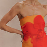 Woman wearing a strapless orange and red ombre chiffon maxi dress with gold hoop earrings — Meshki | Endless UAE