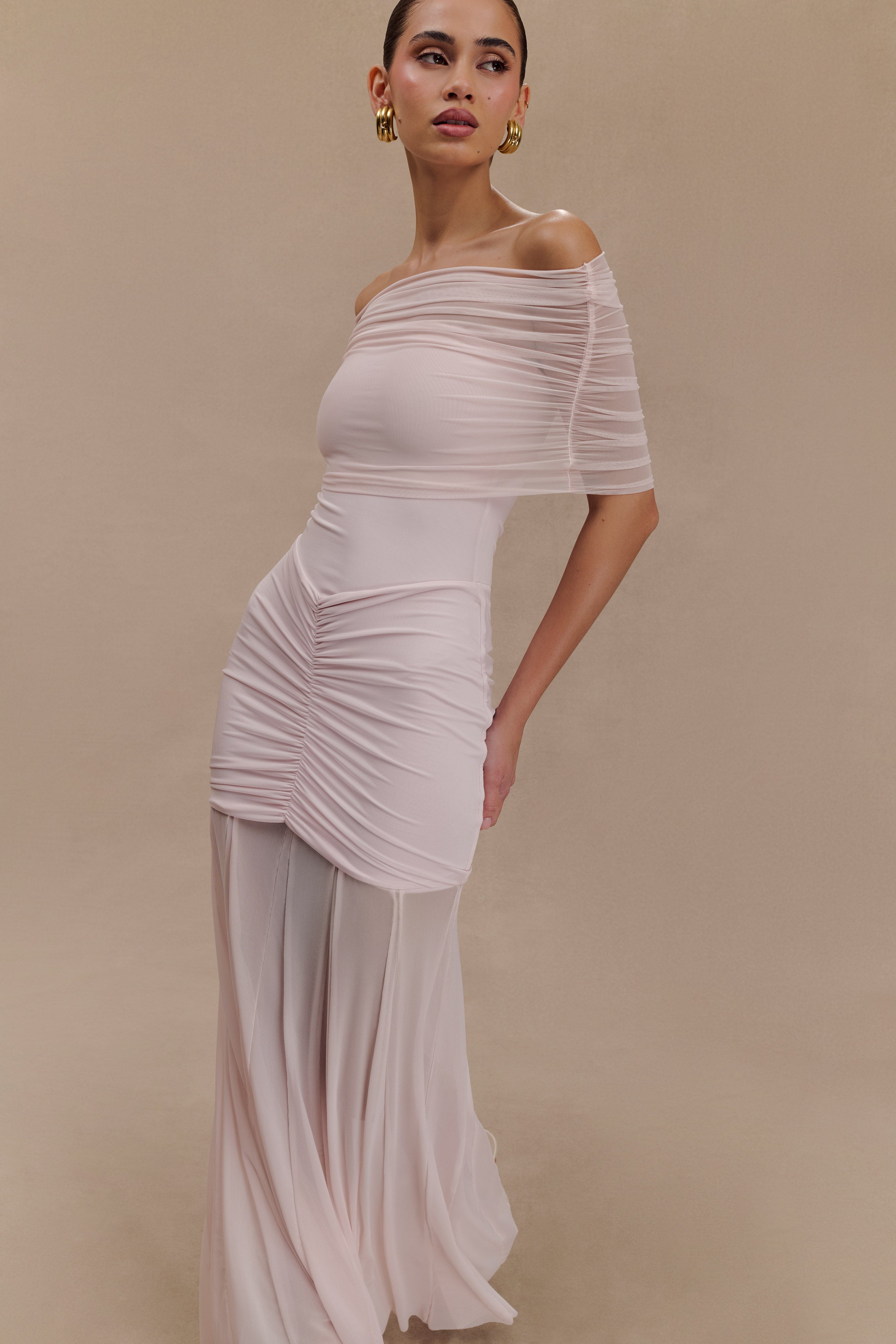 Woman wearing blush off-shoulder maxi dress with ruched details and mesh panel — Meshki | Endless UAE