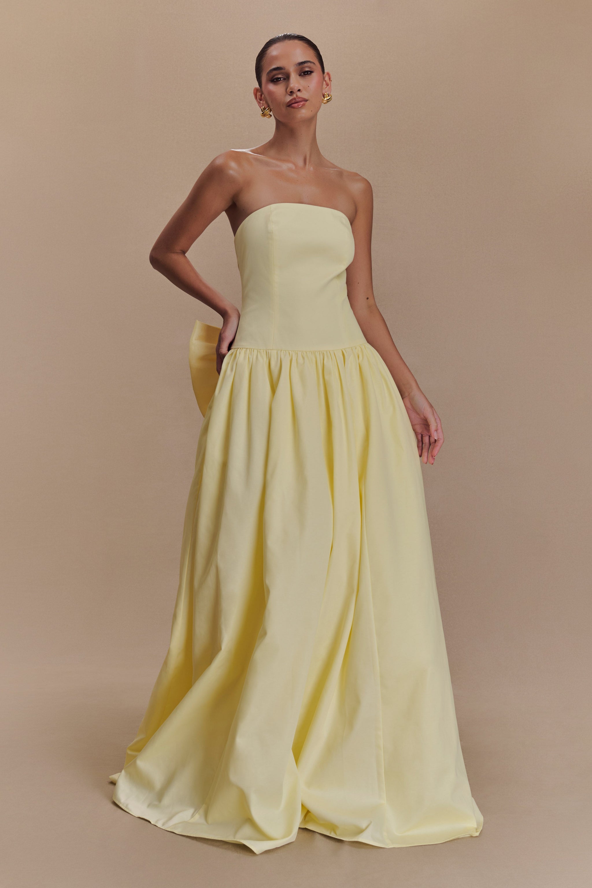 Elegant strapless maxi dress in soft yellow with fitted bodice, gathered drop-waist skirt, and detachable bow detail — Meshki | Endless UAE