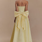 Elegant pale yellow strapless maxi dress with dramatic oversized bow detail at back, floor-length silhouette — Meshki | Endless UAE