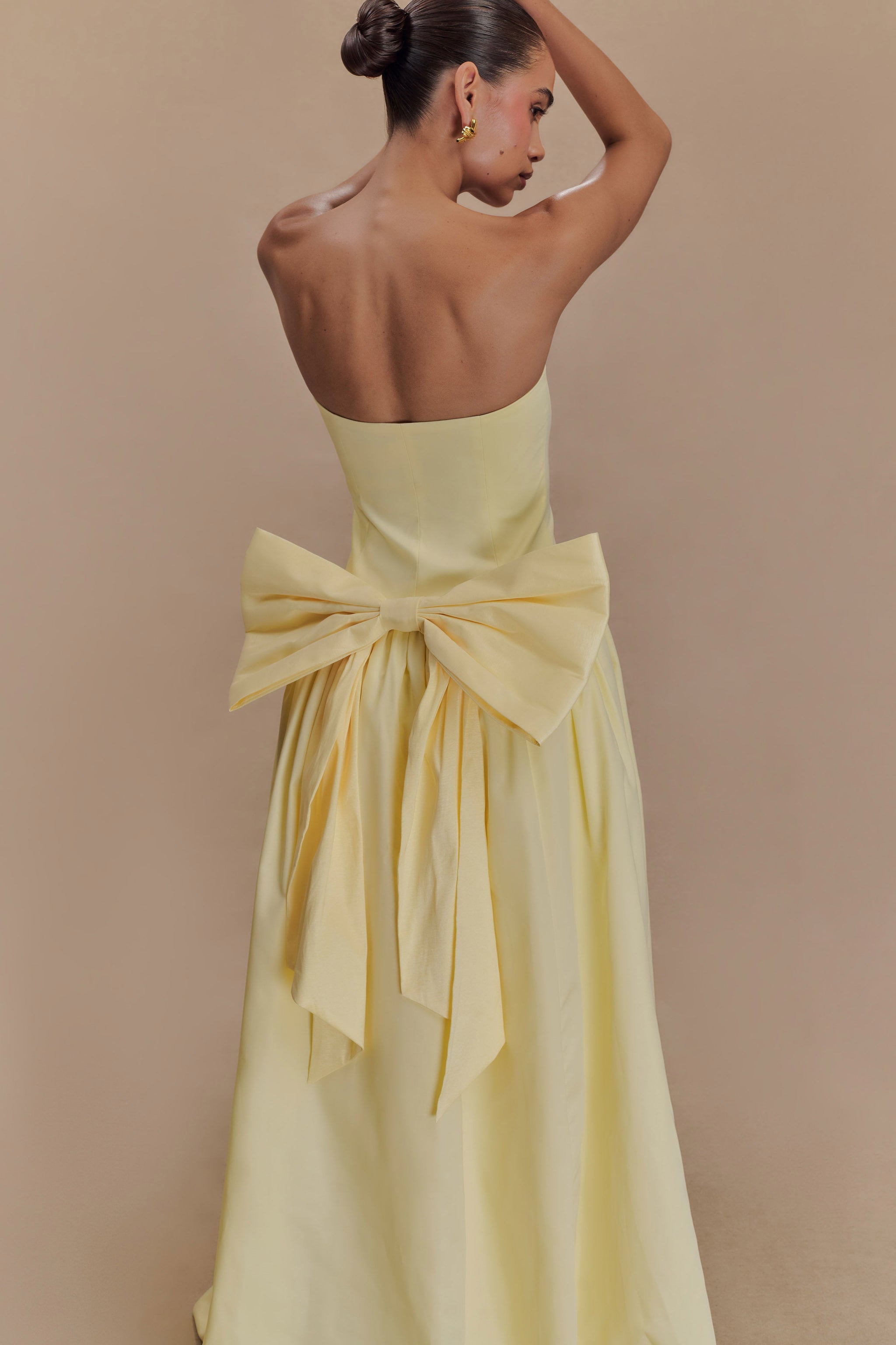 Elegant pale yellow strapless maxi dress featuring a dramatic oversized bow detail at the back waist — Meshki | Endless UAE