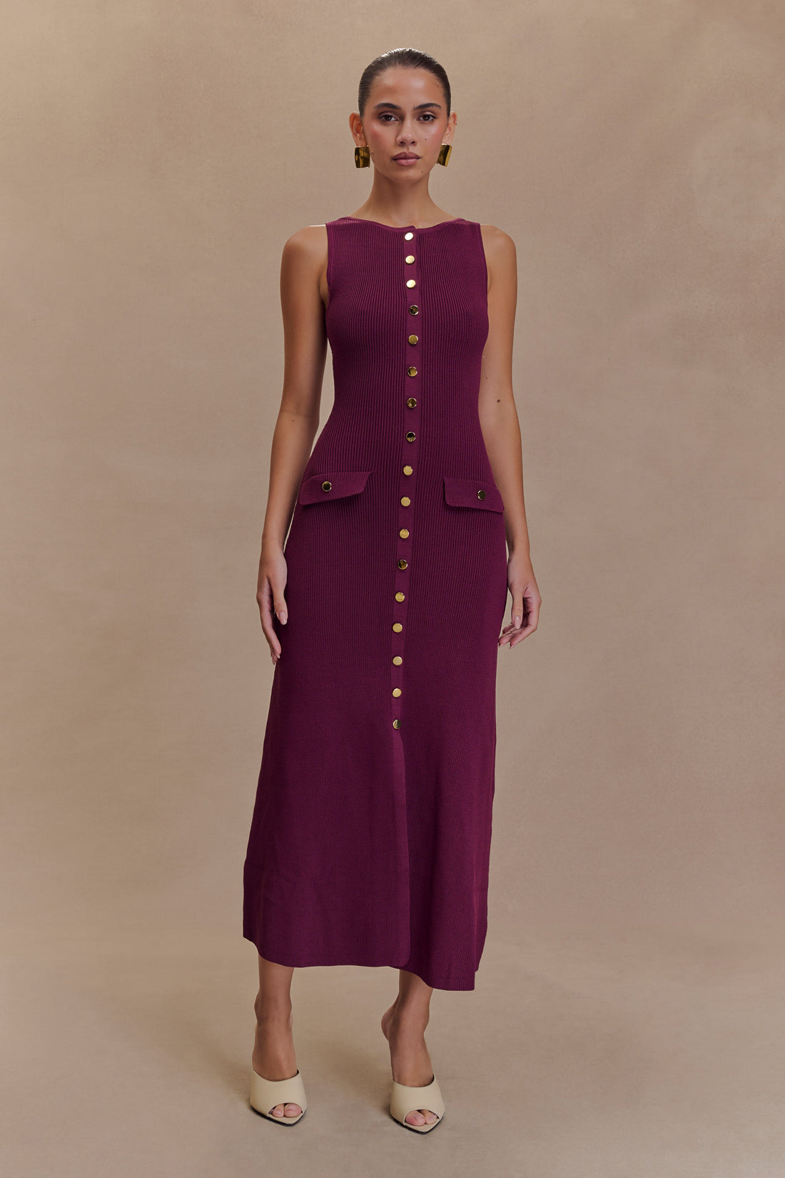 Woman wearing burgundy sleeveless ribbed maxi dress with gold button front detail and flap pockets — Meshki | Endless UAE