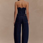 Rear view of woman wearing dark denim strapless corset top with zipper closure and matching wide-leg jeans — Meshki | Endless UAE