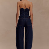 Rear view of woman wearing dark denim strapless corset top with zipper closure and matching wide-leg jeans — Meshki | Endless UAE