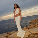 Elegant white sequin two-piece set with one-shoulder crop top and high-waist maxi skirt by ocean at sunset — Label Loft London | Endless UAE