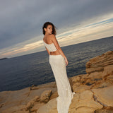 Ivory sequin crop top and maxi skirt set on model by rocky coastline at sunset — Label Loft London | Endless UAE
