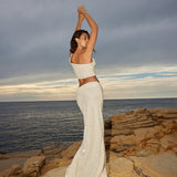 Elegant off-shoulder sequin crop top and maxi skirt set in ivory, worn by model on coastal rocks at sunset — Label Loft London | Endless UAE