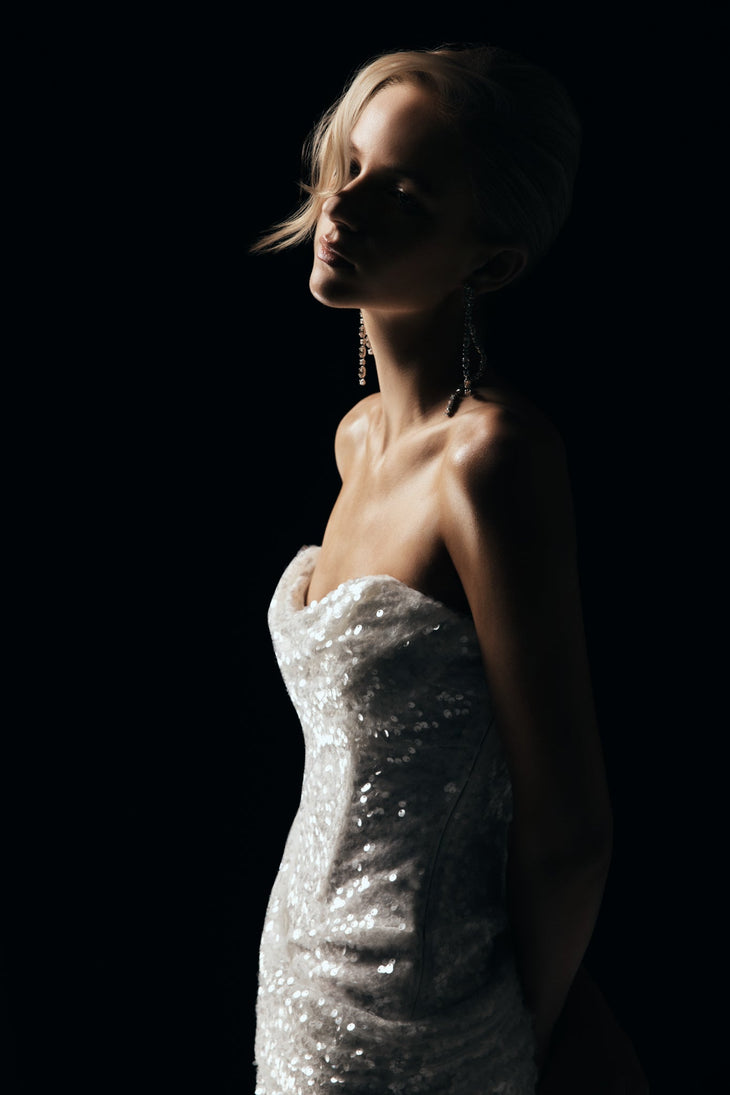 Elegant woman in silver sequin strapless maxi dress against black background — Meshki | Endless UAE