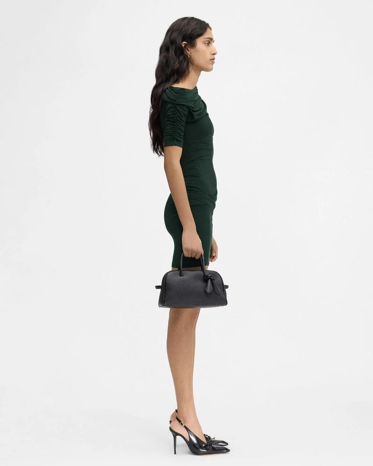 Woman in dark green ruched sleeve mini dress holding black handbag, side view — Jacquemus | Endless UAE