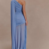 Woman wearing periwinkle blue one shoulder maxi dress with draped fabric detail and cream clutch — Meshki | Endless UAE