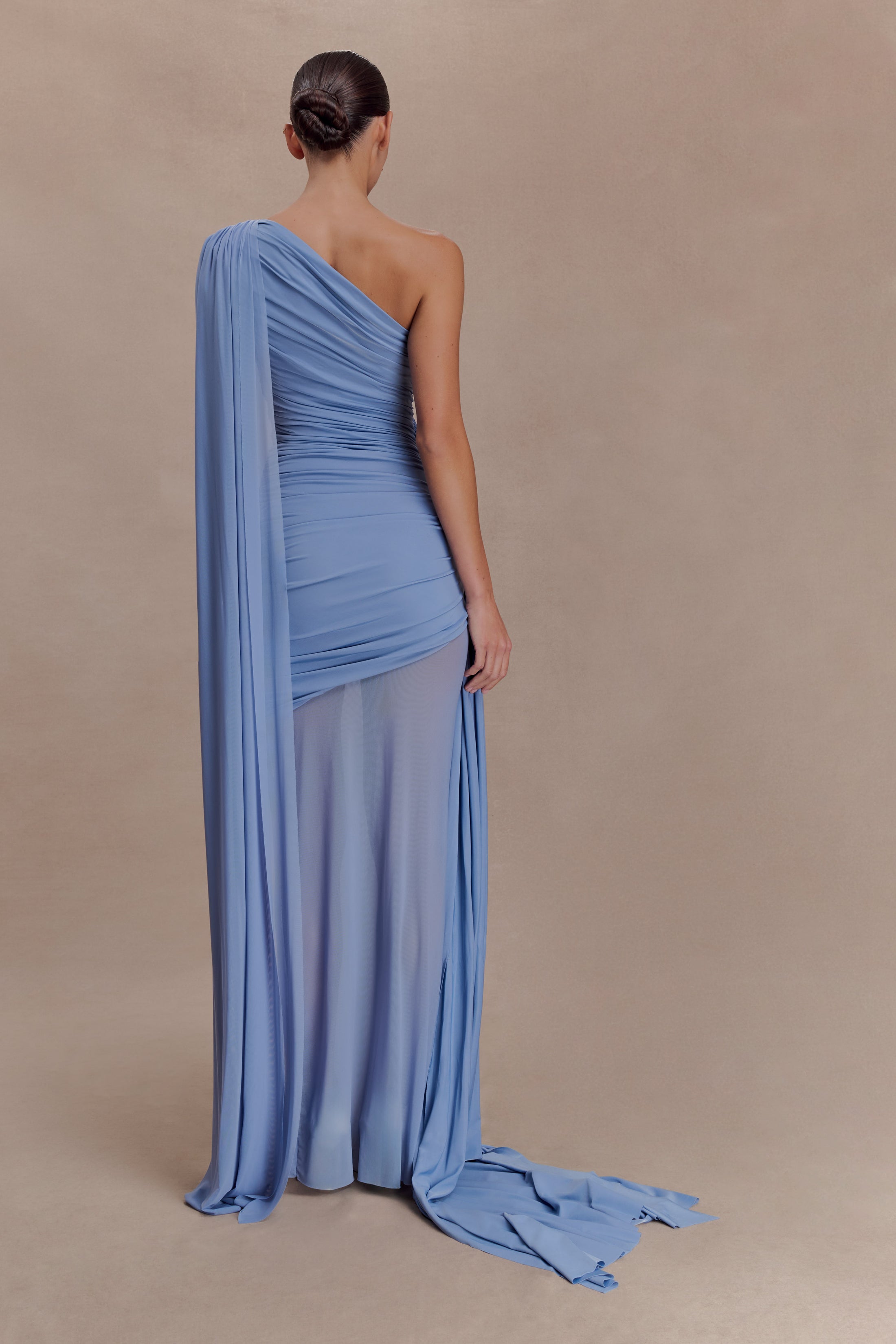 Woman wearing periwinkle blue one shoulder maxi dress with draped fabric detail and cream clutch — Meshki | Endless UAE