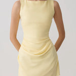 Woman modeling pale yellow sleeveless mini dress with draped side detail and white sandals — Meshki | Endless UAE