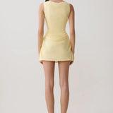 Woman modeling pale yellow sleeveless mini dress with draped side detail and white sandals — Meshki | Endless UAE