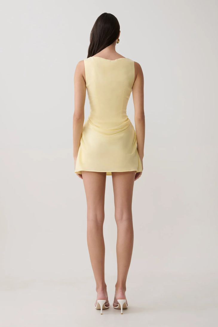 Woman modeling pale yellow sleeveless mini dress with draped side detail and white sandals — Meshki | Endless UAE