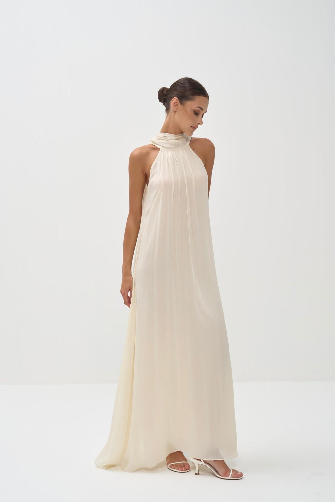 Elegant cream halter neck maxi dress with flowing silhouette and pleated neckline — Nora The Label | Endless UAE
