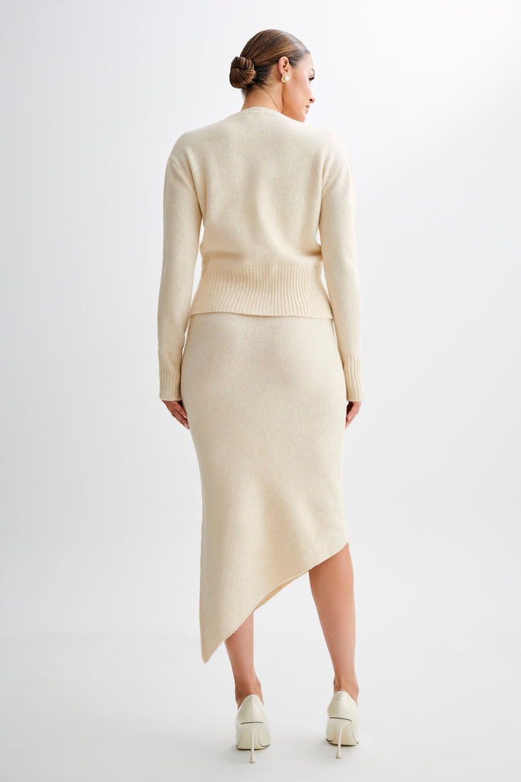 Woman wearing cream knit co-ord set with asymmetric skirt, back view — Meshki | Endless UAE