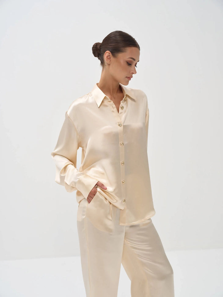 Elegant cream satin pajama set with button-front shirt and matching pants on model against white background — Nora The Label | Endless UAE