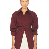 Burgundy poplin button-up shirt styled with cream trousers and black bag — Simon Miller | Endless UAE