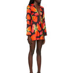 Woman wearing vibrant red and orange strawberry print blazer dress with green handbag — Louisa Ballou | Endless UAE