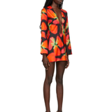 Woman wearing vibrant red and orange strawberry print blazer dress with green handbag — Louisa Ballou | Endless UAE