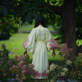 Woman wearing ivory cotton caftan with pink floral embroidery standing in garden with hydrangeas — Yuliya Magdych | Endless UAE