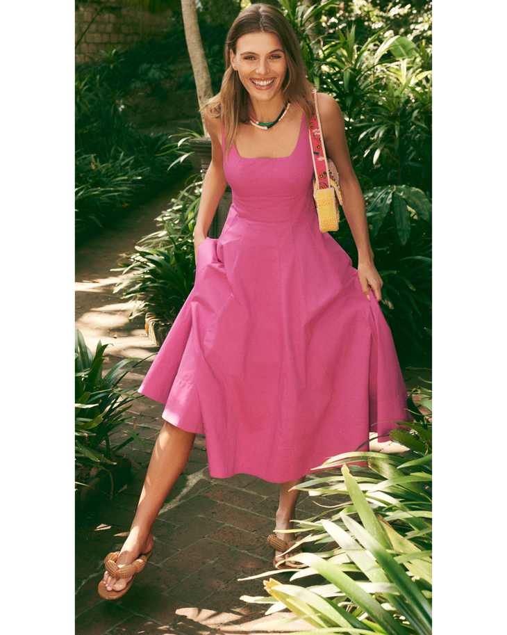 Woman wearing pink midi dress with square neckline and pockets in tropical garden setting — Staud | Endless UAE