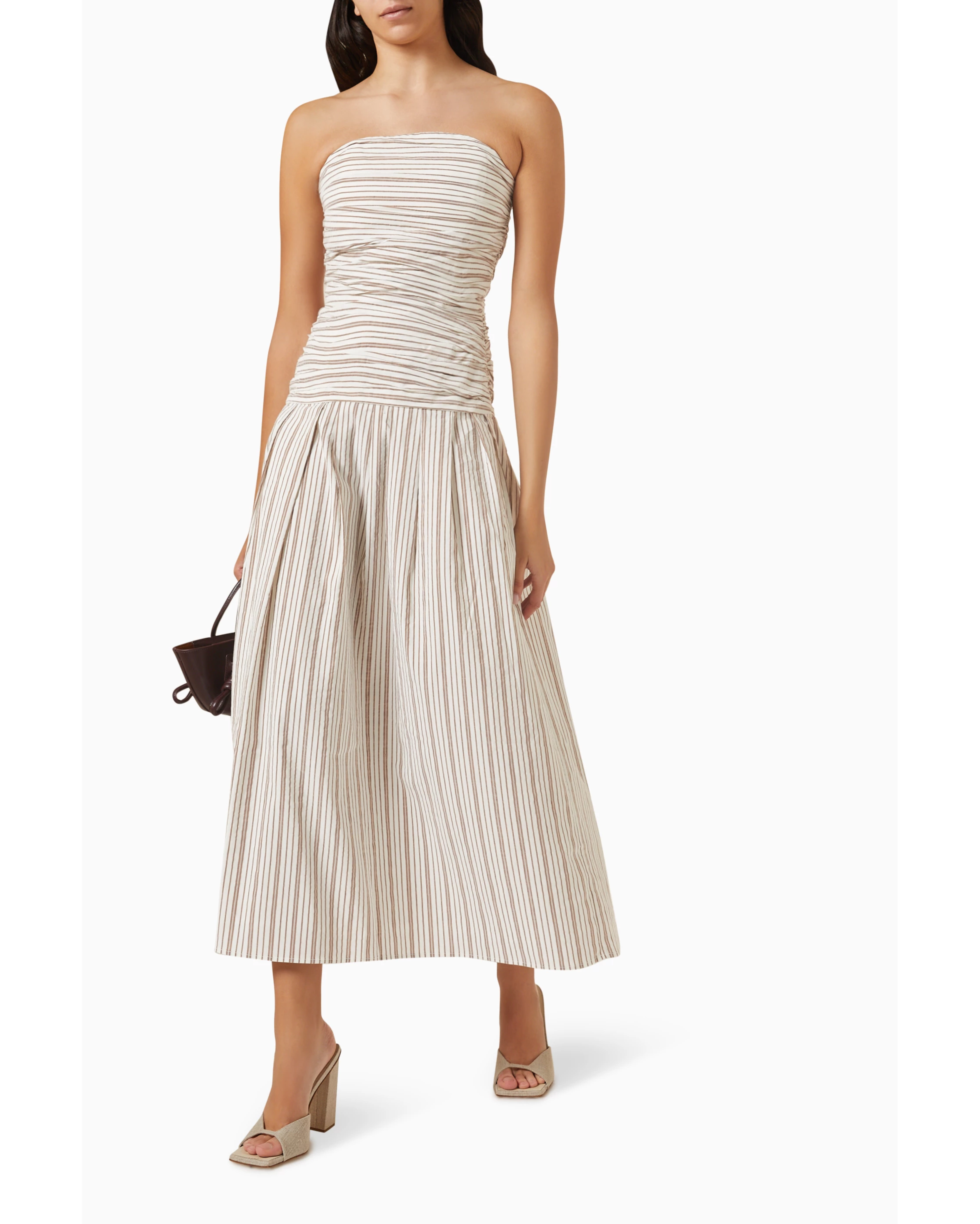 Woman wearing beige and white striped strapless midi dress with pleated skirt — Anna Quan | Endless UAE