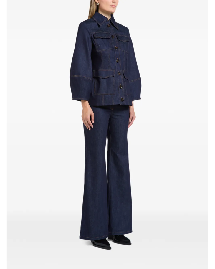 Woman wearing indigo denim jacket and flared jeans with white clutch — Florence & Fortitude | Endless UAE