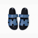 Black leather slide sandals with cutout straps displayed on orange box — Hermès | Endless UAE