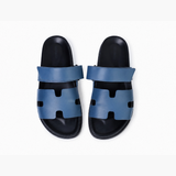 Black leather slide sandals with cutout straps displayed on orange box — Hermès | Endless UAE