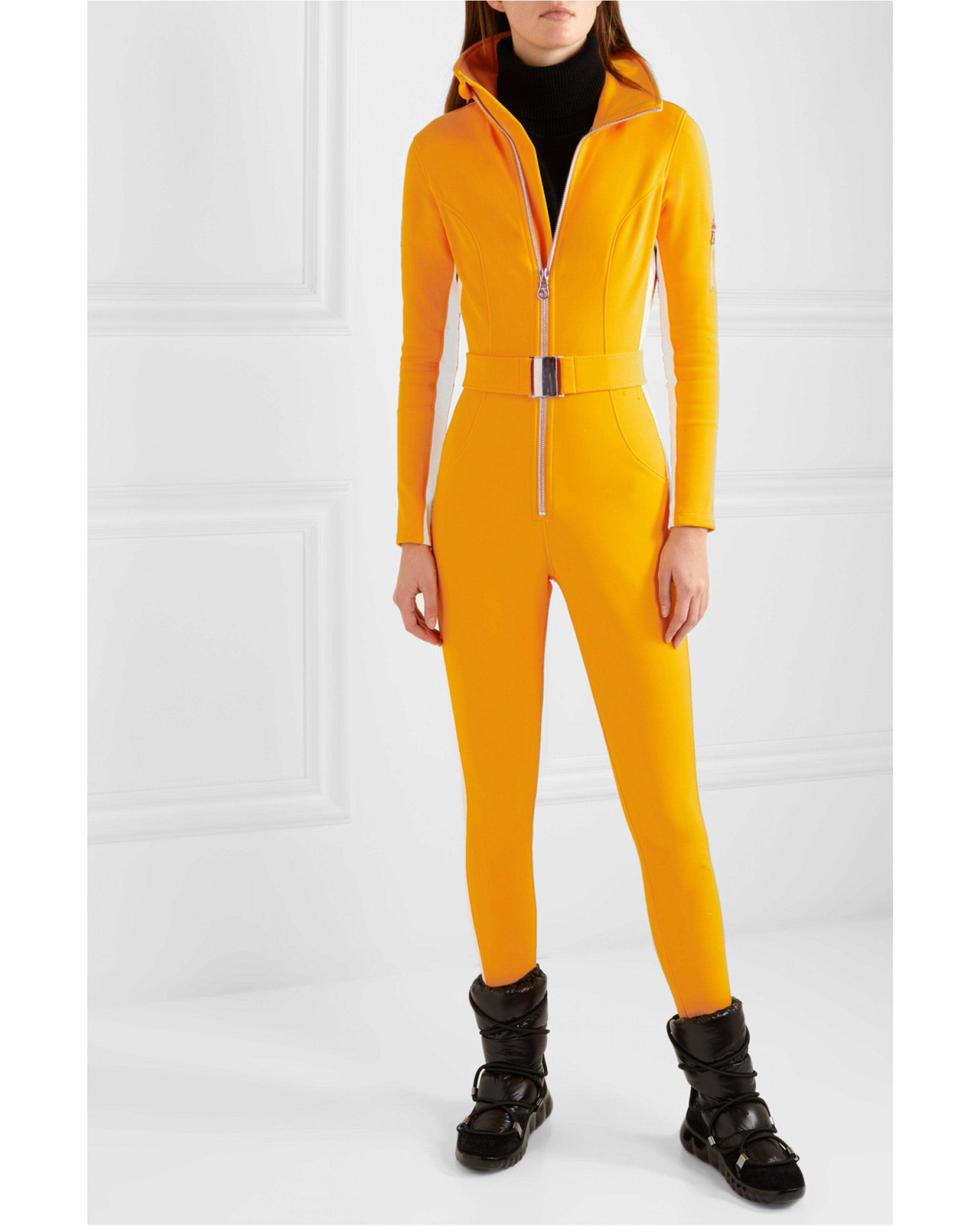 Bright yellow ski suit with belted waist and black turtleneck, paired with black skis — Cordova | Endless UAE