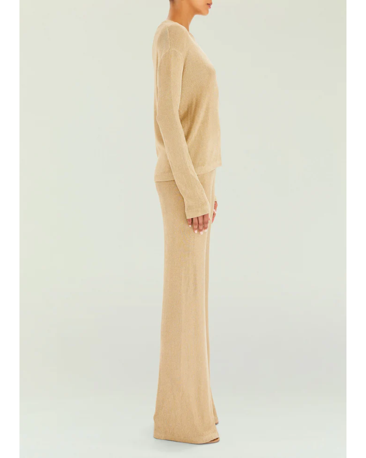 Woman wearing a beige metallic knit top and matching trousers holding a small handbag — SER.O.YA | Endless UAE