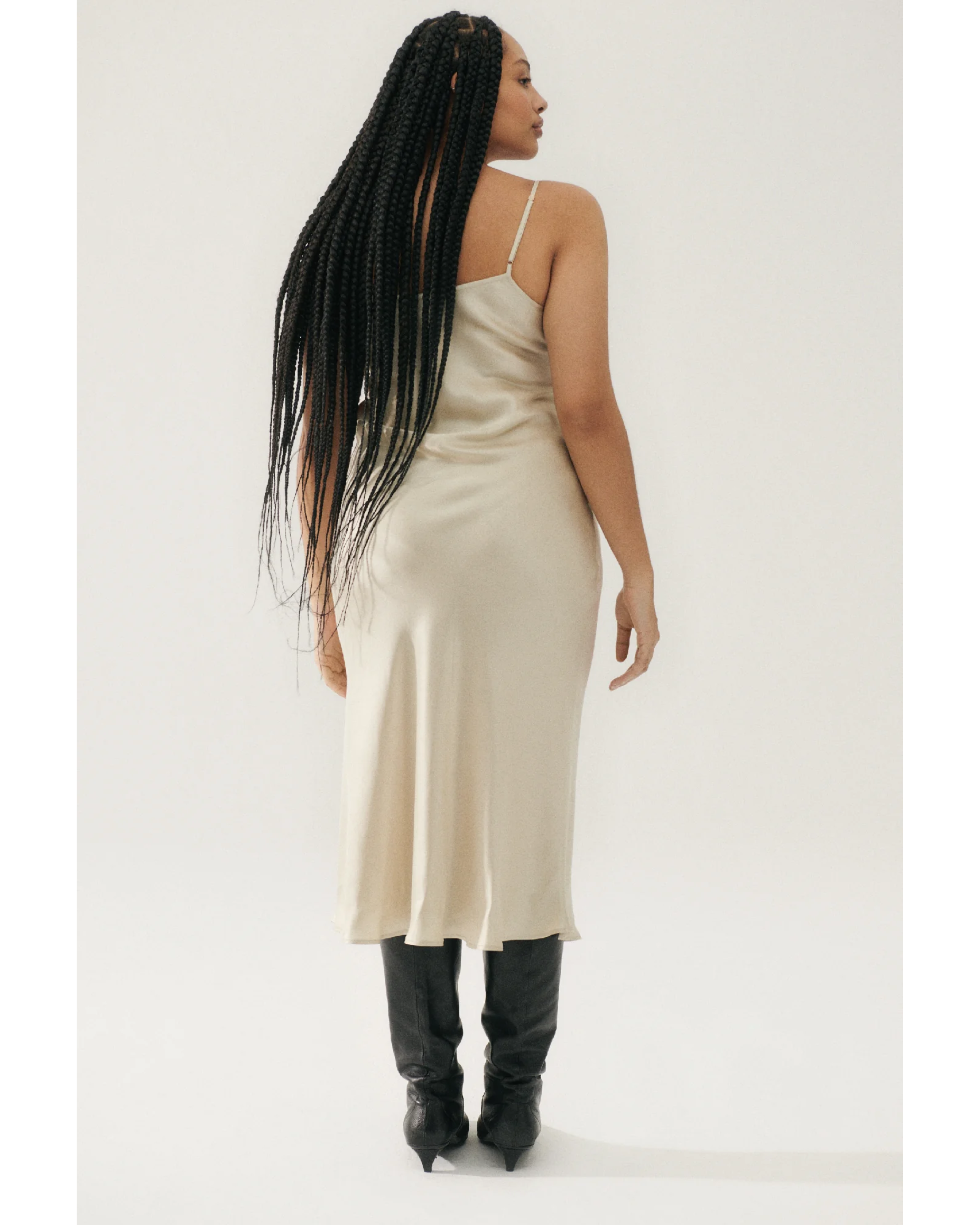 Woman wearing cream spaghetti strap slip dress with black strappy heels — Silk Laundry | Endless UAE