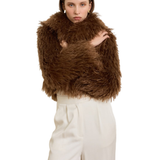 Woman wearing camel-colored fur stole jacket over cream top and pants with burgundy shoes — Madame Magdalena | Endless UAE
