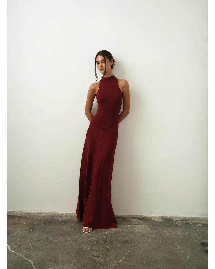Woman wearing burgundy sleeveless halter neck ribbed maxi dress with flowing skirt — Nora The Label | Endless UAE