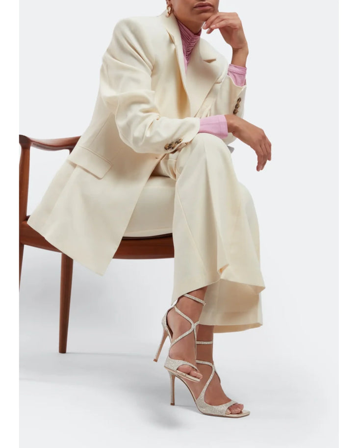 Elegant ivory strappy high-heel sandals with glitter finish worn with cream suit and pink top — Jimmy Choo | Endless UAE