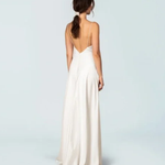 Elegant ivory sleeveless gown with deep V-back, flowing A-line silhouette, and floor-length hem — Fame & Partners | Endless UAE