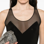 Black maxi dress with sheer mesh panel detail at neckline and racerback design, styled with silver clutch and crystal earrings — Norma Kamali | Endless UAE